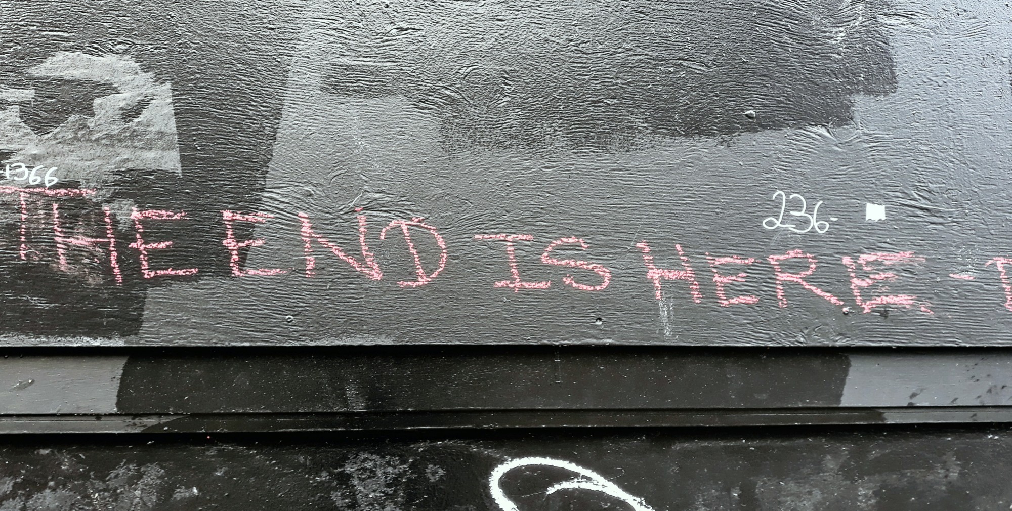 written in pink ink on a building: "the end is here'